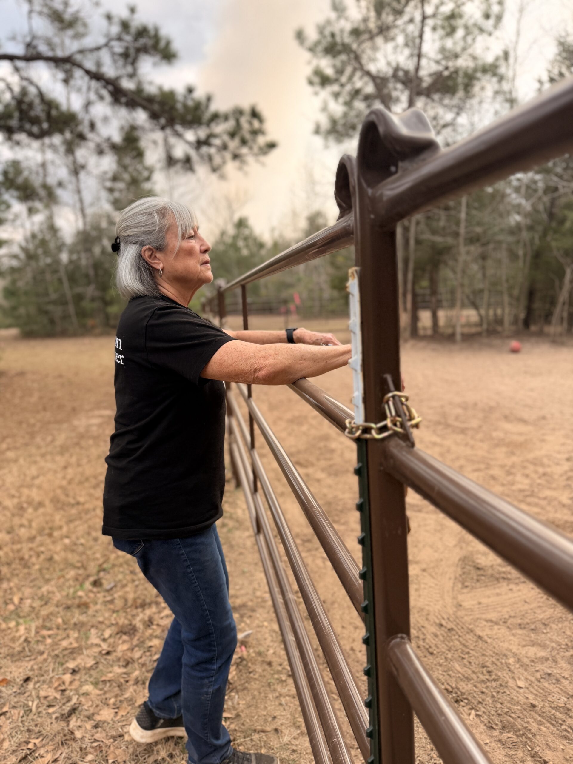Lizette Lobpries leaning on a wooden fence at the Whispers from Peace property