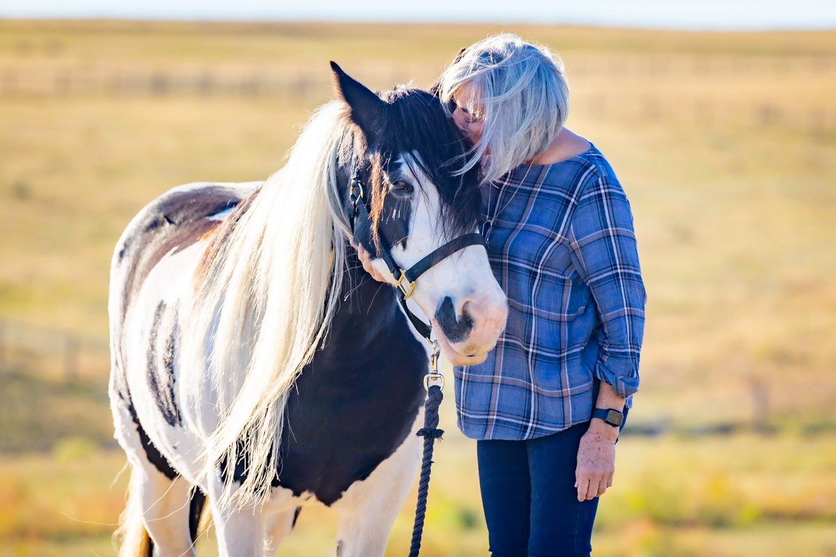 Lizette Lobpries with a paint horse in an open field